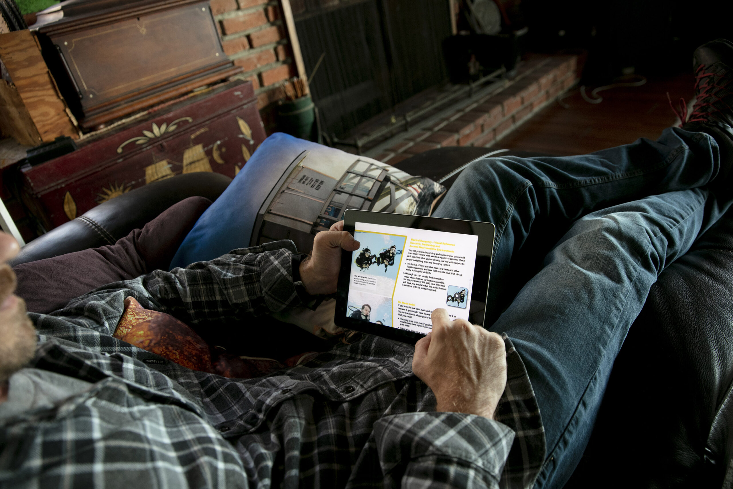Studying a PADI scuba lesson on a tablet while relaxing on a sofa