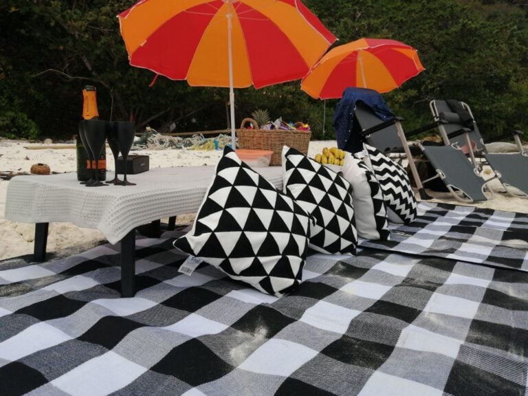 Beach picnic with cushions, mats and parasols beside a low dining table