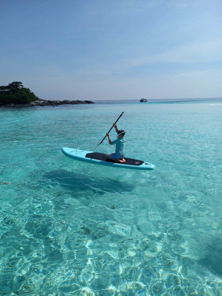 Paddleboarding across clear turquoise water during a private island day trip
