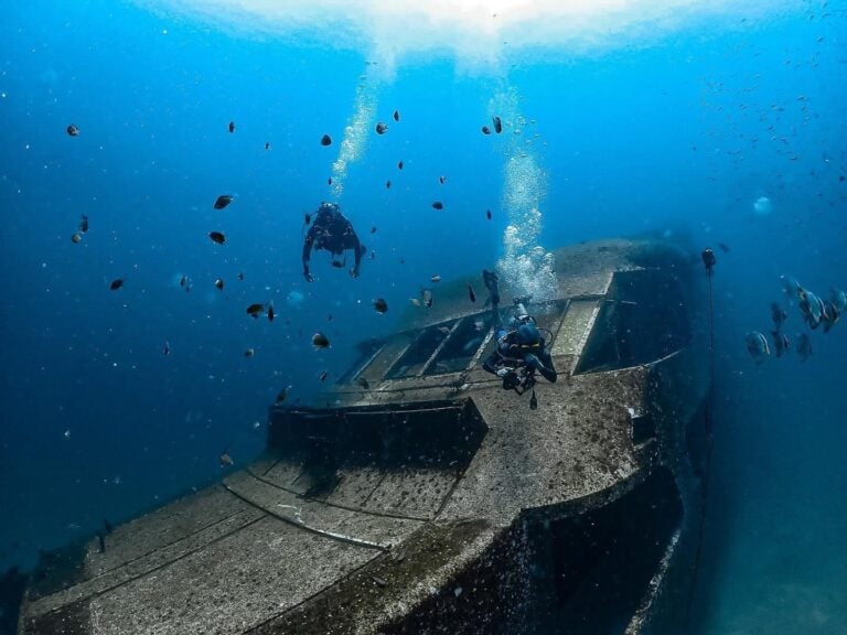 Scuba divers exploring a sunken wreck in the Racha Islands