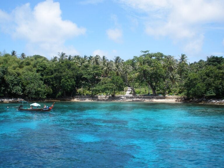 Clear turquoise water and a tree-lined bay at Racha Yai